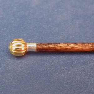 May include: A wooden walking stick with a gold-coloured knob on the end. The knob has a ribbed design.