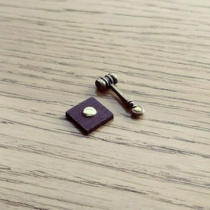 May include: A miniature wooden gavel with a gold-colored top and a small square wooden base.