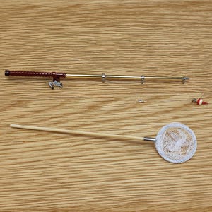May include: A miniature fishing set with a wooden rod, a red and gold fishing reel, a white net, and a red and white bobber.
