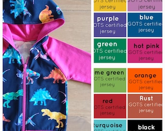 May include: A pink and navy blue hooded sweatshirt with a dinosaur print. The sweatshirt is made from GOTS certified jersey fabric. The colors available are yellow, orchid, purple, blue, green, hot pink, me green, orange, red, rust, turquoise, and black.