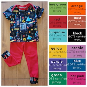 May include: A red and black science-themed baby onesie with a cat, microscope, and other science-related images. The onesie is paired with red pants with the same science-themed print on the cuffs. The image also includes a color chart with various GOTS certified jersey fabric colors.