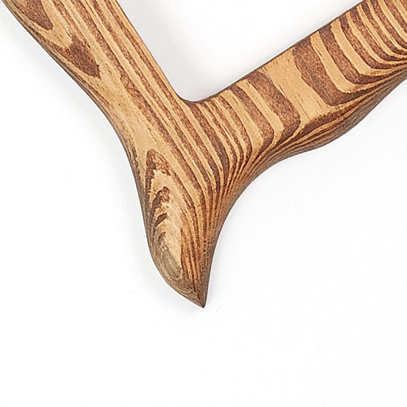 Peut inclure: Un objet en bois en forme de V pr&eacute;sentant un motif de grain naturel prononc&eacute; avec des tons de bois alternant entre le beige clair et le brun fonc&eacute;. La surface est lisse avec un bord inf&eacute;rieur incurv&eacute; et pointu et une texture de bois visible.