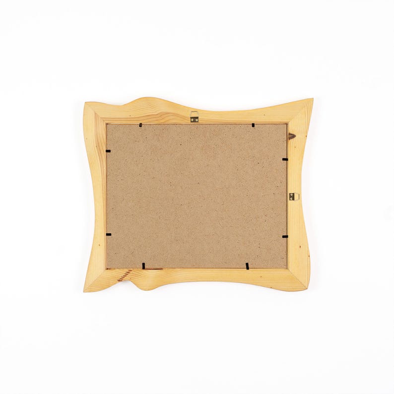 May include: A rectangular picture frame crafted from light-coloured natural wood with an irregular, wavy outer edge. The back of the frame features a brown fibreboard backing secured by several black metal clips and a small metal hanging bracket.