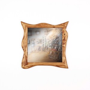 May include: A square wooden mirror with a unique, organic frame. The frame is a warm, light brown color with a natural wood grain texture. The mirror reflects a room filled with artwork.