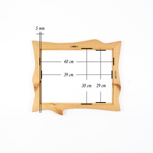 K&ouml;nnte beinhalten: Ein rechteckiger Bilderrahmen aus Holz mit unregelm&auml;&szlig;igem, nat&uuml;rlichem Randdesign. Der Rahmen weist eine sichtbare Holzmaserung und Metallaufh&auml;ngungen auf. Technische Anmerkungen zeigen eine Dicke von 5 mm sowie Innenma&szlig;e von 40 cm mal 30 cm und 39 cm mal 29 cm.