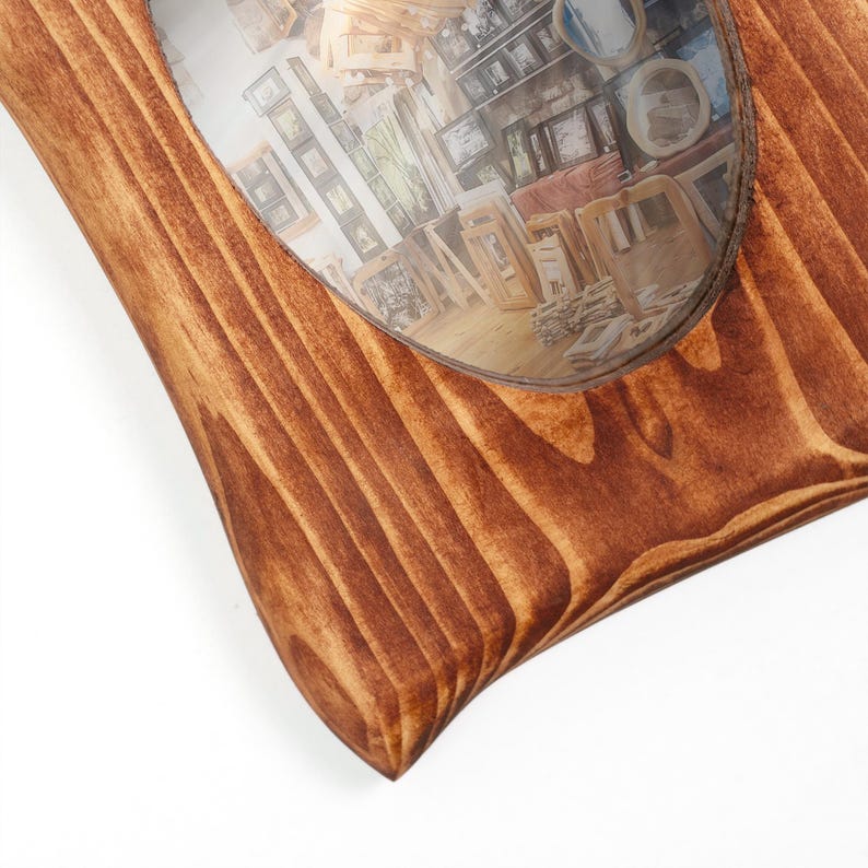 K&ouml;nnte beinhalten: Ein rechteckiger Bilderrahmen aus Holz mit einer satten, mittelbraunen Beizung, die ausgepr&auml;gte Holzmaserungen zeigt. Der Rahmen verf&uuml;gt &uuml;ber eine gro&szlig;e, oval geformte &Ouml;ffnung in der Mitte zur Aufnahme eines Fotos oder Objekts.