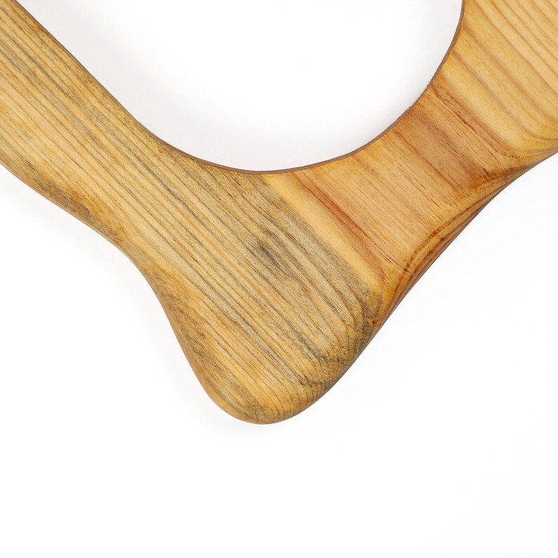 May include: Close-up of a wooden cutting board with a natural wood grain pattern. The board has a curved shape with a smooth, rounded edge. The wood tones range from light tan to medium brown.