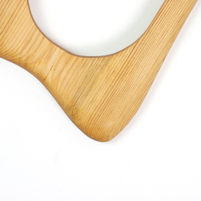 Peut inclure: Un cadre en bois brun clair avec une finition lisse et polie et un motif de grain naturel visible. Le cadre pr&eacute;sente une forme organique incurv&eacute;e avec des bords arrondis et une grande ouverture circulaire vide au centre de la structure.