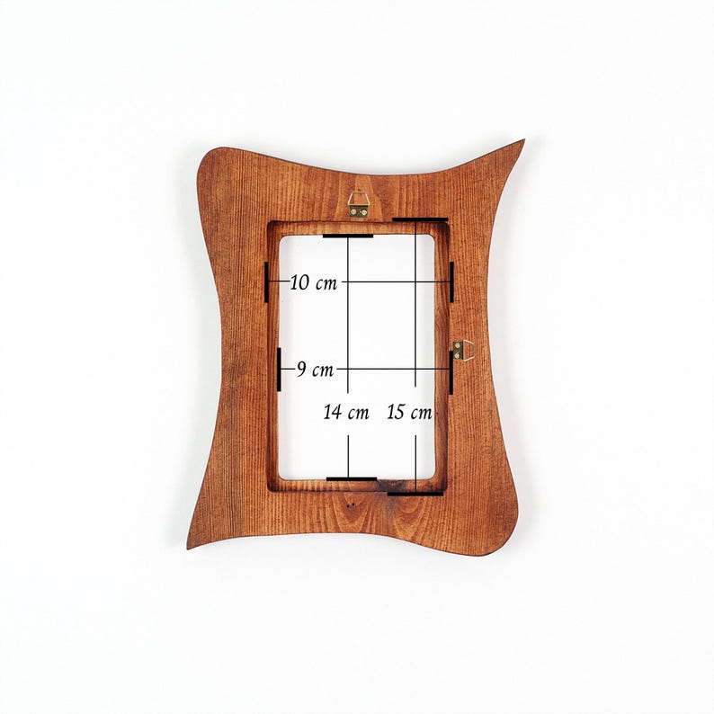 May include: A wooden picture frame with a distinctive, curved shape. The frame is a warm brown colour and features measurements of 10 cm, 9 cm, 14 cm, and 15 cm. It has a rectangular opening and hanging hardware.