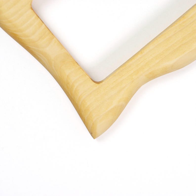 Pu&ograve; includere: Una cornice in legno di colore chiaro con una finitura liscia e lucida e un distinto motivo a venature naturali. La cornice presenta un giunto angolare a forma di V, che mette in mostra le tonalit&agrave; beige chiaro e crema del legno in un design pulito.