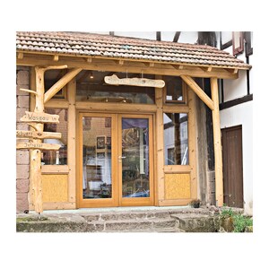 May include: Exterior view of a building with a wooden frame and a tiled roof. The entrance features double glass doors and a sign that reads "Wasgau in Schwarz Infrared". A wooden signpost points towards different directions.