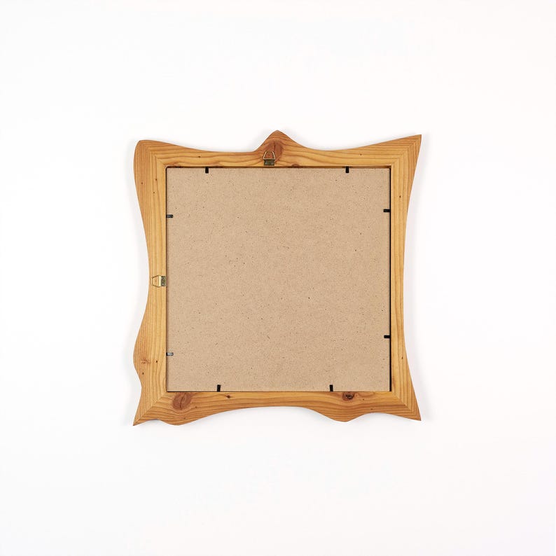 May include: A square, light brown wooden picture frame with a decorative, wavy edge. The frame has a natural wood grain and a cardboard backing. A small metal hanger is attached to the top center.