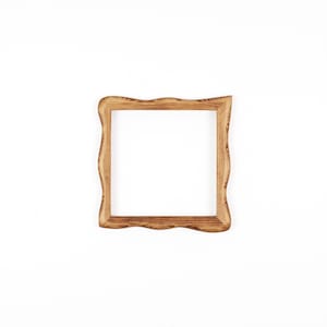 May include: A square wooden picture frame with a natural light brown finish and visible wood grain patterns. The frame features a distinct wavy, organic edge design on all four sides, surrounding a central empty square opening for display.