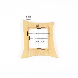 May include: A light-coloured wooden picture frame with a curved, hourglass-like silhouette. The frame features a central square opening measuring 9 cm by 9 cm, with outer dimensions of 10 cm by 10 cm and a thickness of 5 mm, including a metal hanger.