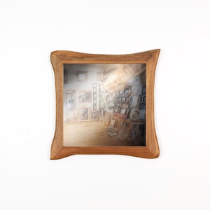 Peut inclure: Cadre photo carr&eacute; en bois avec un bord ondul&eacute;. Le cadre est de couleur marron chaud et contient une image de style aquarelle d'un atelier d'art rempli de peintures et de miroirs.