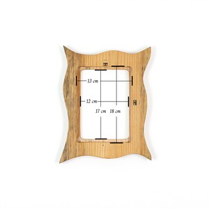 Pu&ograve; includere: Una cornice in legno con un design ondulato unico. L'apertura della cornice misura 17 cm per 12 cm, con dimensioni complessive di 18 cm per 13 cm. La cornice &egrave; in legno chiaro.