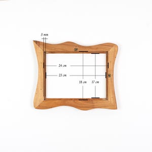 Op de afbeelding: Een houten fotolijst met een golvende rand. De binnenafmetingen van de lijst zijn 24 cm bij 18 cm. De lijst is 5 mm dik. De lijst heeft een ophangbeugel aan de achterkant.