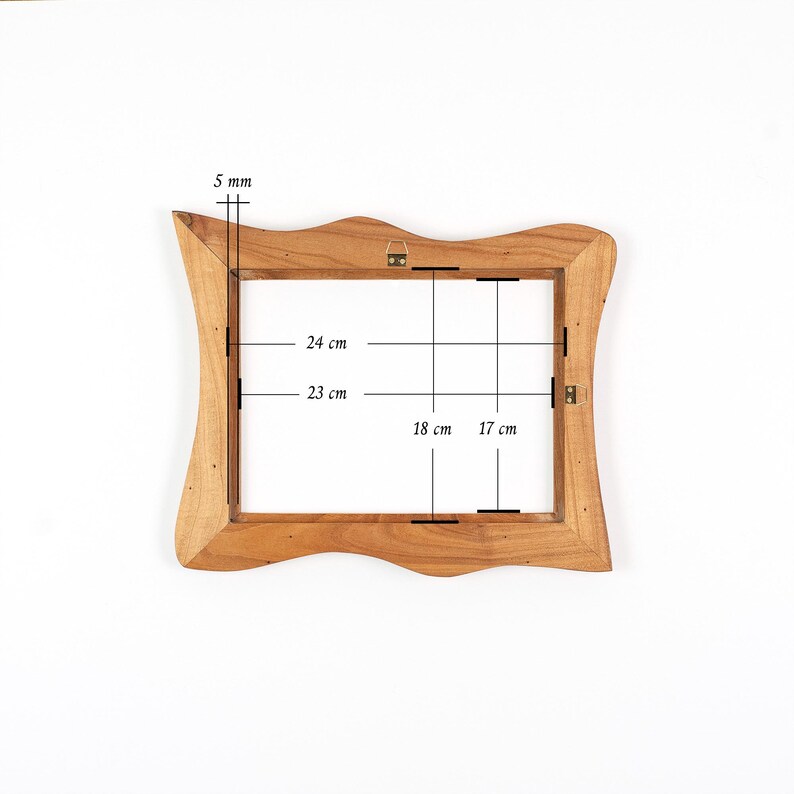 Op de afbeelding: Een houten fotolijst met een golvende rand. De binnenafmetingen van de lijst zijn 24 cm bij 18 cm. De lijst is 5 mm dik. De lijst heeft een ophangbeugel aan de achterkant.
