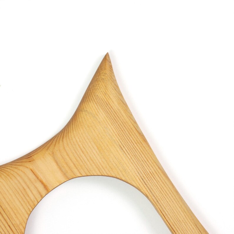Peut inclure: Un objet en bois brun clair avec une surface lisse et incurv&eacute;e et une pointe saillante. Le grain du bois est clairement visible, suivant des lignes parall&egrave;les le long de la structure, qui pr&eacute;sente une grande section d&eacute;coup&eacute;e arrondie.
