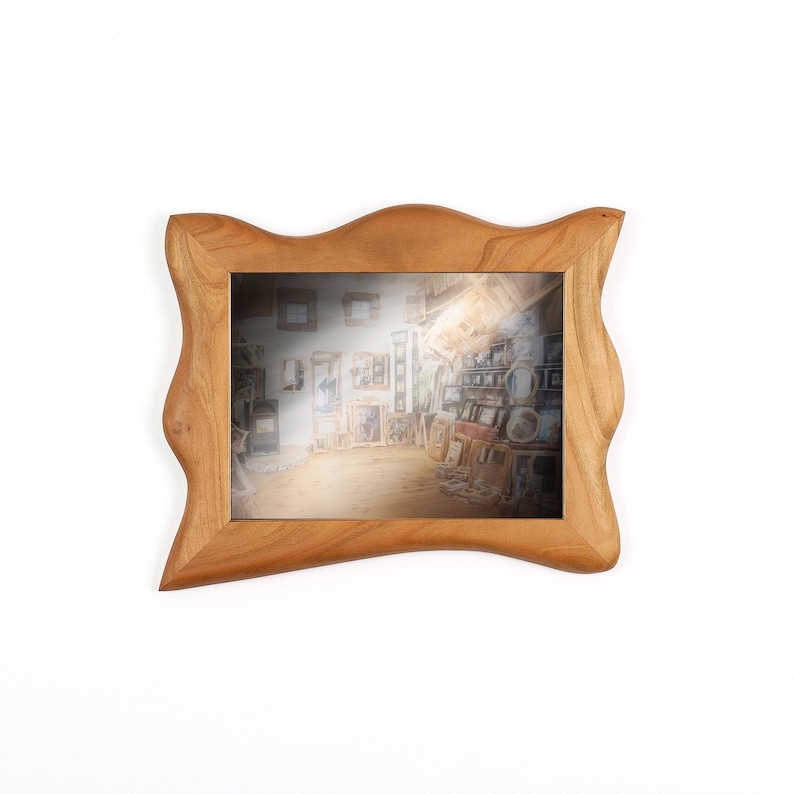 Puede incluir: Un marco de fotos de madera marr&oacute;n claro con una forma ondulada y org&aacute;nica. El marco contiene una imagen de una habitaci&oacute;n llena de obras de arte. El marco es de madera y tiene un acabado natural.