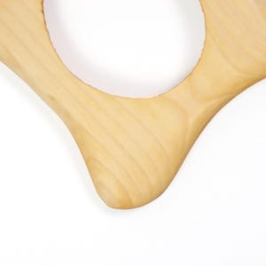 K&ouml;nnte beinhalten: Ein helles Holzservierbrett mit einer einzigartigen, organischen Form. Das Brett hat einen gro&szlig;en, kreisf&ouml;rmigen Ausschnitt in der Mitte und ein glattes, geschwungenes Design. Die Holzmaserung ist sichtbar und tr&auml;gt zur nat&uuml;rlichen &Auml;sthetik bei. Ideal zum Servieren von Vorspeisen.