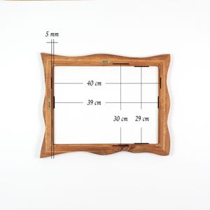 May include: A wooden picture frame with a wavy edge. The frame's interior dimensions are 11.4 inches by 15.7 inches. The frame's exterior dimensions are 15.7 inches by 18.1 inches. The frame is 0.2 inches thick.