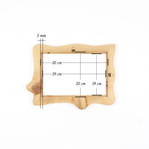 Puede incluir: Un marco de fotos de madera natural clara con un borde org&aacute;nico irregular. El marco presenta vetas de madera visibles y herrajes met&aacute;licos para colgar. Las anotaciones t&eacute;cnicas indican un grosor de 5 mm, con dimensiones internas de 29 cm por 19 cm y externas de 30 cm por 20 cm.