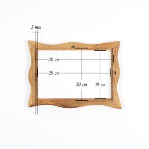 Puede incluir: Un marco de fotos de madera marr&oacute;n claro con un borde ondulado. Las dimensiones interiores del marco son de 29 cm por 19 cm, y el marco tiene un grosor de 5 mm. El marco est&aacute; vac&iacute;o y listo para una foto o una obra de arte.