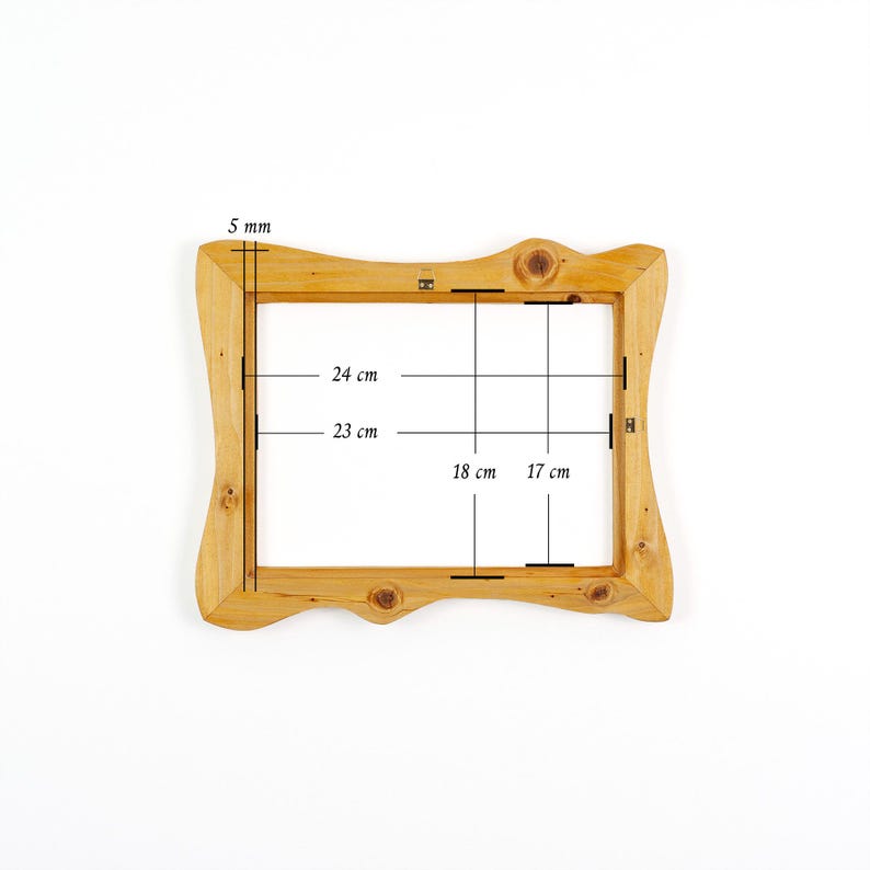 Może przedstawiać: Jasna drewniana rama do zdjęć z dekoracyjną, falistą krawędzią. Wymiary ramy podano w centymetrach: 24 cm, 23 cm, 18 cm i 17 cm. Grubość ramy wynosi 5 mm.