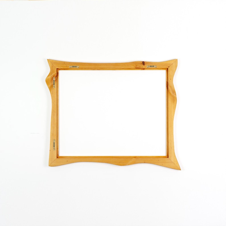 May include: A rectangular wooden picture frame with a light brown natural wood grain finish. The frame features wavy, organic edges on the left and right sides. Metal hanging hardware is attached to the back of the frame on the top and side.