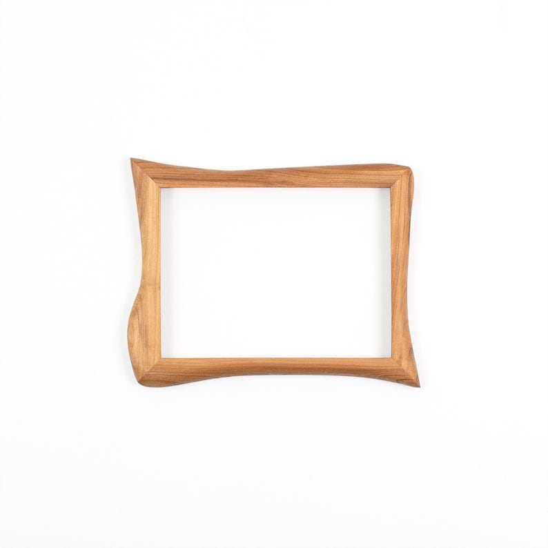May include: A rectangular wooden picture frame with a natural light brown finish and visible wood grain. The frame features an irregular, wavy outer edge on the left and right sides, while the inner opening remains a standard rectangle.