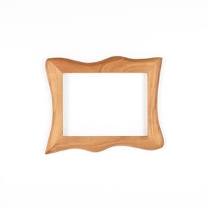 Op de afbeelding: Een lichtbruine houten fotolijst met een uniek, golvend ontwerp. De lijst heeft een rechthoekige opening en is gemaakt van lichtgekleurd hout. De lijst is leeg en klaar voor een foto of kunstwerk.