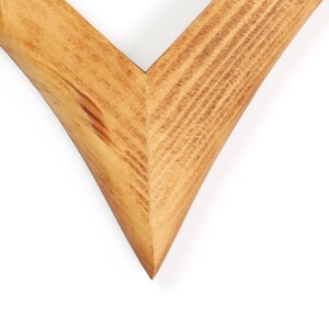 K&ouml;nnte beinhalten: Eine V-f&ouml;rmige Holzrahmenecke mit einer hellbraunen, nat&uuml;rlichen Holzmaserung. Die beiden Holzteile sind in einem scharfen Gehrungswinkel verbunden und zeigen die glatte Textur sowie die ausgepr&auml;gten linearen Muster der Holzmaserung.