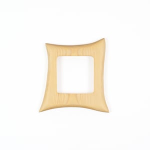 May include: A light-coloured wooden picture frame with a square central opening and four concave sides. The frame features a visible natural wood grain pattern throughout its surface, with smooth, curved edges that taper towards the corners.