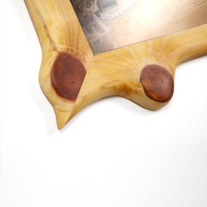 May include: A rectangular picture frame crafted from light-colored natural wood with a smooth, polished finish. The frame features prominent, dark brown circular wood knots at the corners and along the edges, highlighting the organic grain.