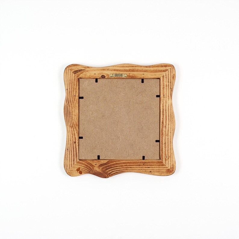 K&ouml;nnte beinhalten: Ein quadratischer Bilderrahmen aus Holz mit einem wellenf&ouml;rmigen Rand. Der Rahmen besteht aus hellbraunem Holz und hat eine Kartonr&uuml;ckwand. Die R&uuml;ckseite des Rahmens hat schwarze Laschen, um ein Bild zu halten.