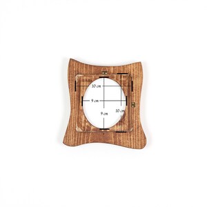 Pode incluir: Uma moldura de madeira com um formato curvo &uacute;nico. A moldura tem uma abertura oval central, com dimens&otilde;es de 9 cm por 10 cm. A moldura &eacute; feita de madeira marrom clara e tem uma apar&ecirc;ncia r&uacute;stica.