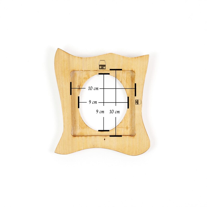 K&ouml;nnte beinhalten: Ein hellfarbiger Holzbilderrahmen mit quadratischer &Ouml;ffnung und wellenf&ouml;rmigen Kanten. Die &Ouml;ffnung misst 9 cm x 10 cm. Der Rahmen hat einen kleinen Aufh&auml;ngemechanismus auf der R&uuml;ckseite.
