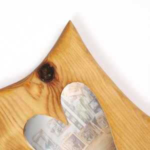 Puede incluir: Un marco de fotos de madera con un recorte en forma de coraz&oacute;n. El marco es de madera clara con vetas visibles y un nudo. La abertura en forma de coraz&oacute;n revela un vistazo del fondo, un collage de fotos enmarcadas.