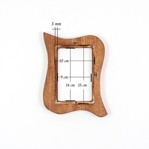 May include: A brown wooden picture frame with a distinctive, curved shape. The frame is 5 mm thick. The internal dimensions are 9 cm by 15 cm. The frame is designed to hold a 10 cm by 14 cm photo.