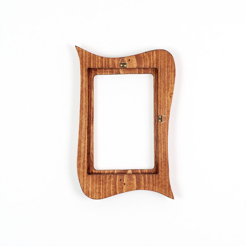 May include: A wooden picture frame with a distinctive, curved design. The frame is stained a warm brown colour and has a rectangular opening. Metal hardware is attached for hanging.
