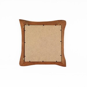 Peut inclure: Vue arri&egrave;re d'un cadre photo carr&eacute; en bois avec une finition marron chaud. Le cadre a un design incurv&eacute; unique sur les bords ext&eacute;rieurs. Le dos comporte un support en carton et du mat&eacute;riel de suspension.