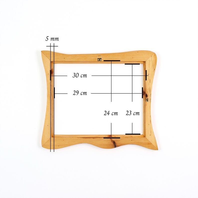 May include: A light-colored wooden picture frame with wavy edges. The frame features a metal hanging bracket on the top center. Technical markings indicate a frame thickness of 5 mm, with internal dimensions of 30 cm by 29 cm and 24 cm by 23 cm.