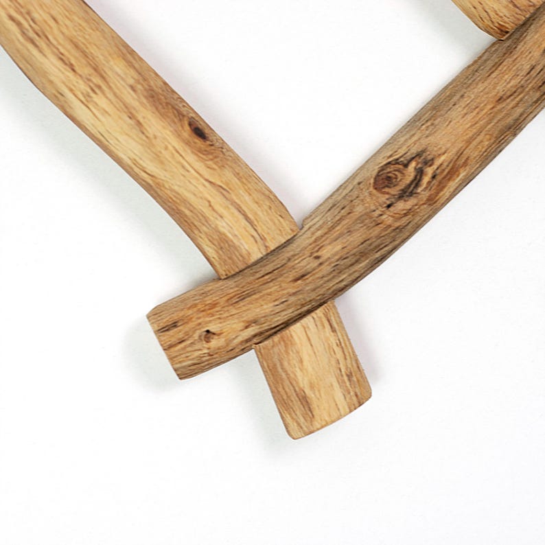 Pode incluir: Uma moldura em forma de cora&ccedil;&atilde;o constru&iacute;da com duas pe&ccedil;as de madeira natural castanho-claro com veios e n&oacute;s vis&iacute;veis. Os dois ramos de madeira est&atilde;o unidos no ponto inferior, sobrepondo-se para formar um V com extremidades arredondadas.