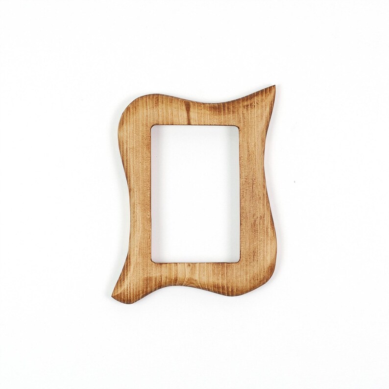 May include: A wooden picture frame with a distinctive, undulating shape. The frame is rectangular with a central aperture and is crafted from light brown wood. The edges have a slightly weathered appearance, enhancing its rustic appeal.