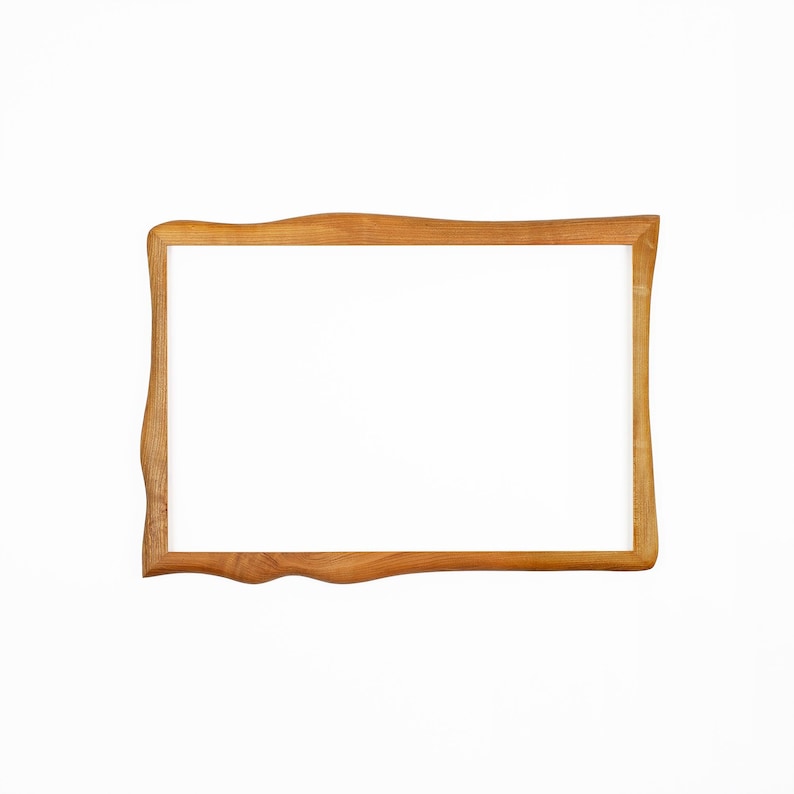 Pu&ograve; includere: Una cornice rettangolare in legno con finitura in legno naturale. La cornice ha un design a bordo unico e ondulato e l'interno &egrave; bianco. La cornice &egrave; posta su uno sfondo bianco.