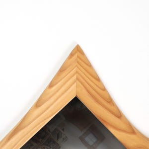 May include: A wooden picture frame with a light brown finish. The frame is triangular, with a mitered corner. The wood grain is visible. The frame is set against a white background.