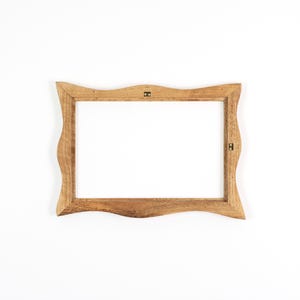 Puede incluir: Un marco de fotos de madera marr&oacute;n claro con un borde ondulado e irregular. El marco tiene una abertura rectangular. Se ve el herraje met&aacute;lico para colgar en la parte posterior.