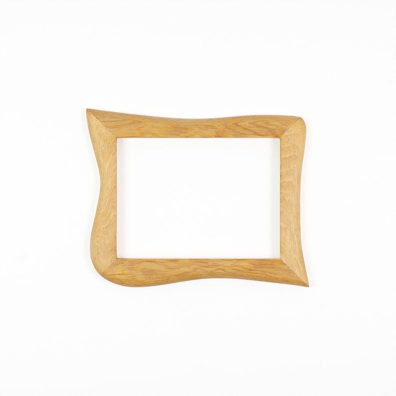 May include: A rectangular wooden picture frame with a light brown natural wood grain finish. The frame features a distinct wavy, organic contour along its outer edges, while the inner opening remains a standard rectangular shape for display.