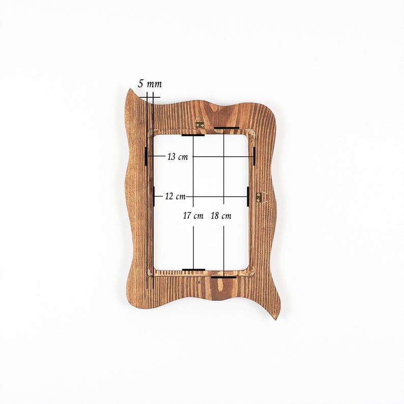 Peut inclure: Un cadre photo rectangulaire en bois avec un bord ext&eacute;rieur ondul&eacute; et irr&eacute;gulier et une finition en grain de bois brun naturel. Le cadre pr&eacute;sente des dimensions int&eacute;rieures de 13 cm sur 17 cm, des dimensions ext&eacute;rieures de 18 cm sur 12 cm et une &eacute;paisseur de 5 mm.